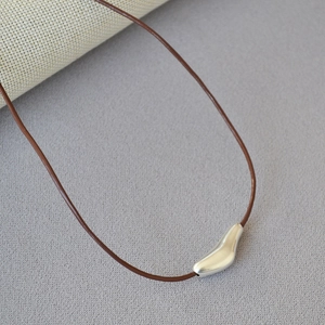 Detail of silver organic drop pendant on brown cord necklace with a minimalist aesthetic