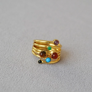 Close-up of multilayer spiral gold ring with six colorful round natural stone inlays