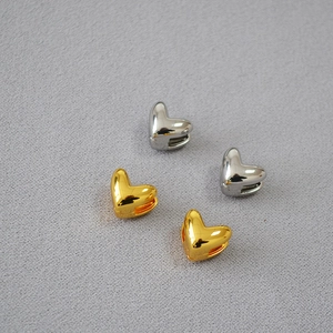 Gros plan sur des perles en forme de cœur polies en plaqué or et argent pour bijoux