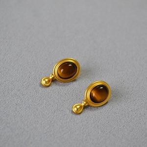 Macro shot of vintage teardrop earrings with oval tiger eye stones in matte gold setting