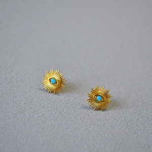 Detailed view of evil eye stud earrings in gold-plated brass with turquoise stones