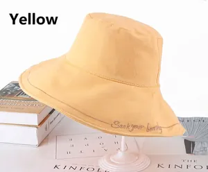 Close-up of bright yellow cotton bucket hat with 'Seek your beauty' embroidery detail
