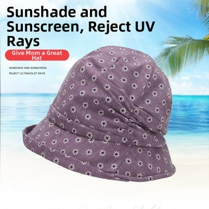 Close-up of foldable purple floral sun hat with white daisy print against beach background