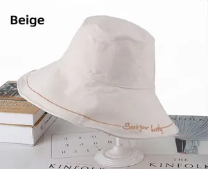 Detail of beige cotton bucket hat featuring Seek Your Beauty embroidery and stitching