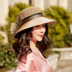 Detail view of woven straw hat with champagne gold bow and black lace netting for women