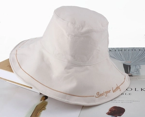 Detail of light beige cotton bucket hat showing decorative stitching and heart embroidery