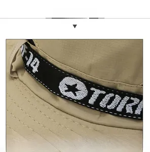 Detail of khaki outdoor hat featuring black mesh ribbon and TORK star embroidery