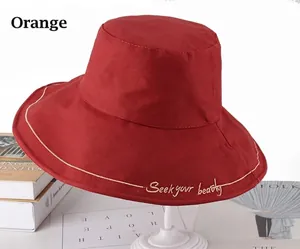 Detail of orange cotton bucket hat featuring Seek your beauty golden embroidery