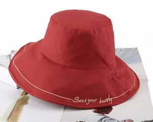 Detailed embroidery of Seek Your Beauty on a brick red cotton sun bucket hat brim