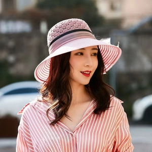 Detail of pink knitted sun hat with mesh top and striped brim worn by a model outdoors