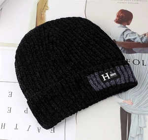 Detail of black knit beanie with fleece lining showing textured weave and brand patch