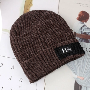 Close-up of brown chenille knit beanie with striped texture and leather logo patch