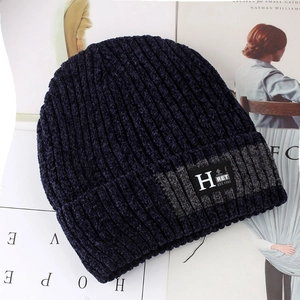 Close-up of winter knit beanie with thick fleece lining and letter H patch on blue fabric