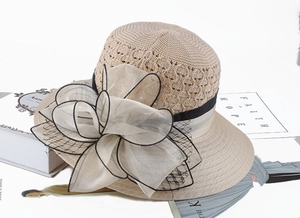 Detail of summer straw hat featuring hollow-out knit texture and oversized organza flower