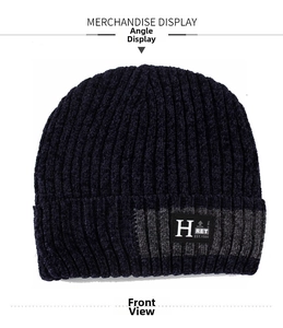 Detailed close-up of dark blue knit beanie featuring grey stripes and retro text patch