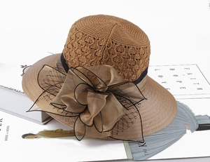 Macro detail of summer knit straw hat featuring an oversized organza flower and mesh ribbon