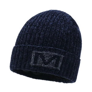 Detailed close-up of dark blue knit beanie with ribbed texture and plush M embroidery