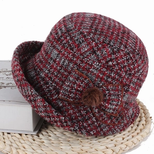 Détail d'un chapeau cloche en tweed rouge à carreaux avec nœud et pompon en fourrure