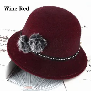 Detail of wine red faux mink bucket hat with dual grey fur balls and woven band
