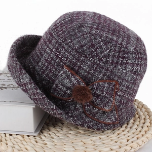 Détail d'un chapeau cloche d'hiver en tweed violet avec nœud tissé et pompon en fourrure