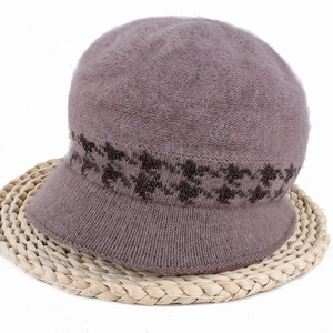 Detail of purple plush knit bucket hat with plaid ribbon band on a woven mat