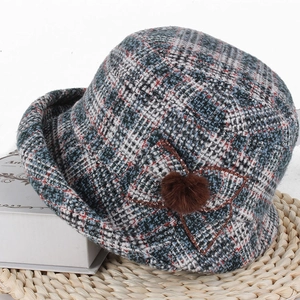 Détail d'un bob à carreaux bleus pour femmes avec fleur en tissu et pompon en fourrure