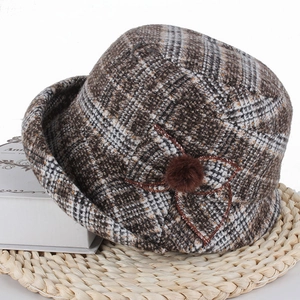 Détail du chapeau cloche d'hiver à carreaux marron avec nœud et pompon décoratif