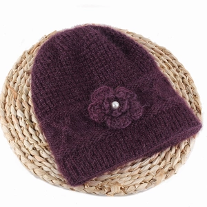 Close-up of deep purple knit hat with wool texture and a pearl-centered flower