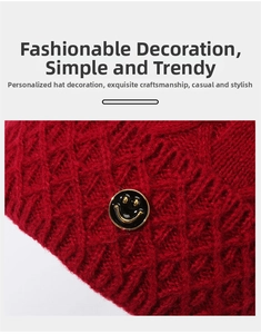 Detailaufnahme der roten gestrickten Beanie mit goldenem Smiley-Zierknopf für Damen