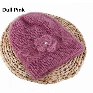 Detail of dusty pink knit hat with floral embellishment and pearl center on soft fabric