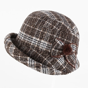 Détail d'un chapeau en tweed d'hiver avec un nœud latéral et un pompon en peluche