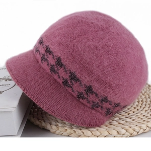 Detail of plush pink knitted hat with visor and sequin accents on a woven mat