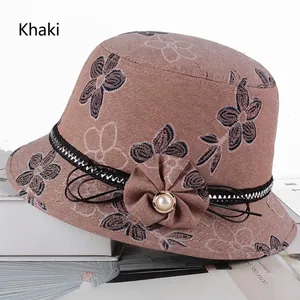 Détail d'un chapeau cloche kaki avec fleur en tissu, perle et bordure en dentelle