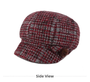 Detail view of red and black tweed newsboy cap with decorative pom pom detail