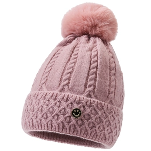 Detailansicht einer rosa Strickmütze mit flauschigem Kunstfellbommel und Smiley-Metallabzeichen