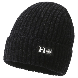 Detailed close-up of a black knit beanie featuring a white 'H' letter patch and ribbed texture