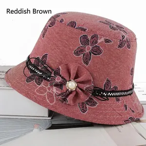 Détail d'un chapeau cloche floral marron rouge avec ruban tressé, nœud et perle