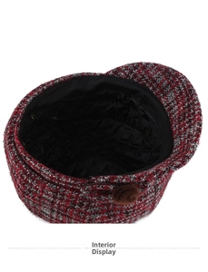 Detail of the black quilted rhombic lining and faux fur pom-pom on the newsboy hat