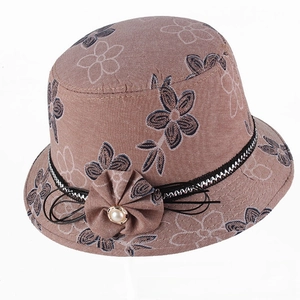 Détail d'un chapeau de soleil à fleurs avec fleur en tissu et perle sur tissu marron