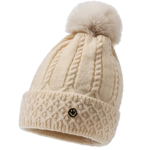 Nahaufnahme der cremefarbenen Strickmütze mit Zopfmuster, Bommel und Smile-Abzeichen
