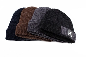 Detail of four colorful knit beanies showing thick chenille texture and letter K patch