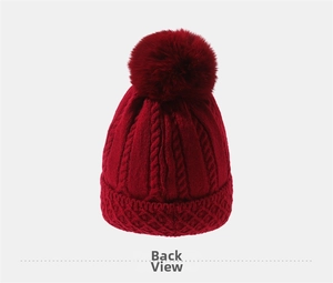 Detail der roten Zopfstrick-Mütze mit dicker Wintertextur und flauschigem Bommel oben