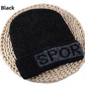Close-up of black knit beanie with SPOR text on straw mat for winter warmth