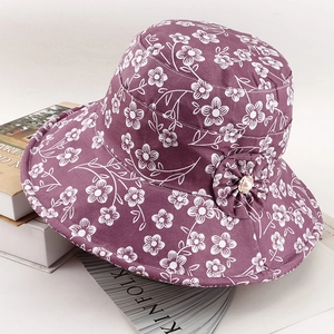 Detail of floral purple sun hat featuring a fabric flower accent with a white pearl center
