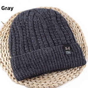 Detail of dark grey knit beanie showing ribbed texture and black quality fashion label