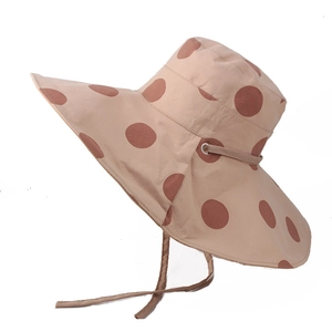 Detail of polka dot sun hat with wide brim, metal eyelets, and adjustable chin strap