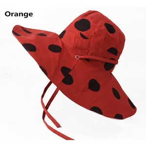 Women's wide brim sun hat with large black polka dots on orange fabric for beach sun protection