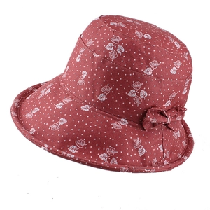 Close-up of red sun hat with white leaf print, bow detail, and cotton-linen texture