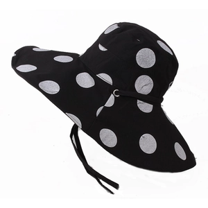 Detail of wide brim sun hat with white polka dots on black and adjustable chin strap