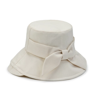 Detail of elegant beige bucket hat featuring a large fabric bow on high-quality canvas